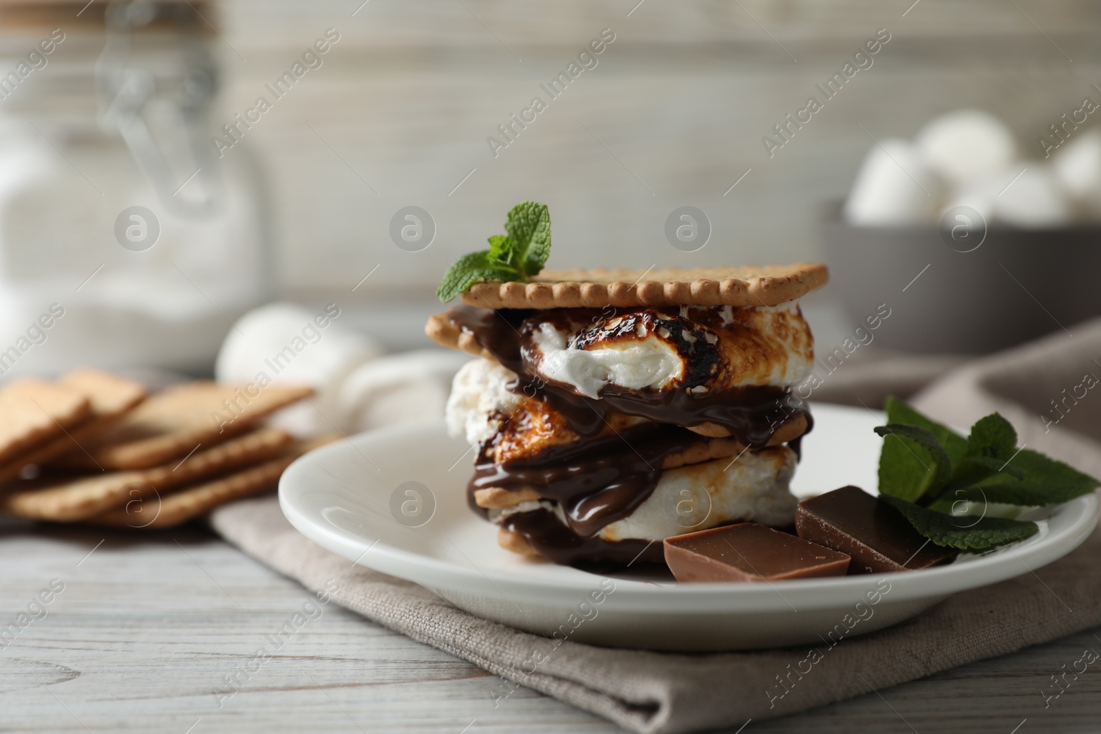 Photo of Delicious marshmallow sandwich with cracker and chocolate on white wooden table, closeup. Space for text