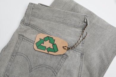 Photo of Jeans with recycling label on white background, top view