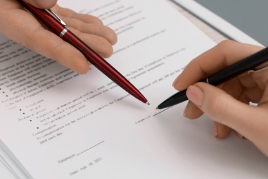 Photo of Man pointing at document and woman putting signature, closeup view
