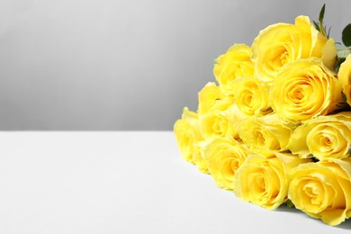 Photo of Beautiful bouquet of yellow roses on light blue table, space for text