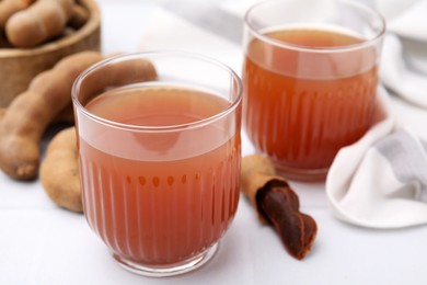 Photo of Tamarind juice and fresh fruits on white table, closeup