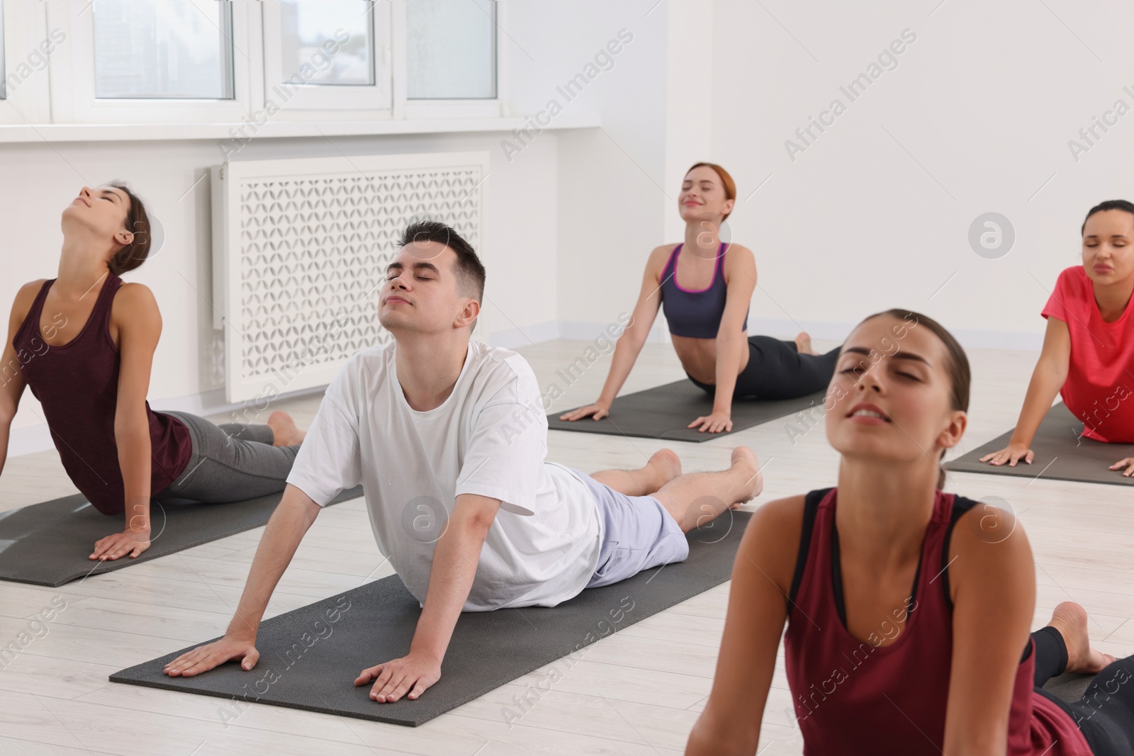 Photo of Group of people practicing yoga on mats indoors