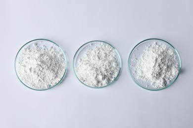 Photo of Petri dishes with calcium carbonate powder on white table, flat lay