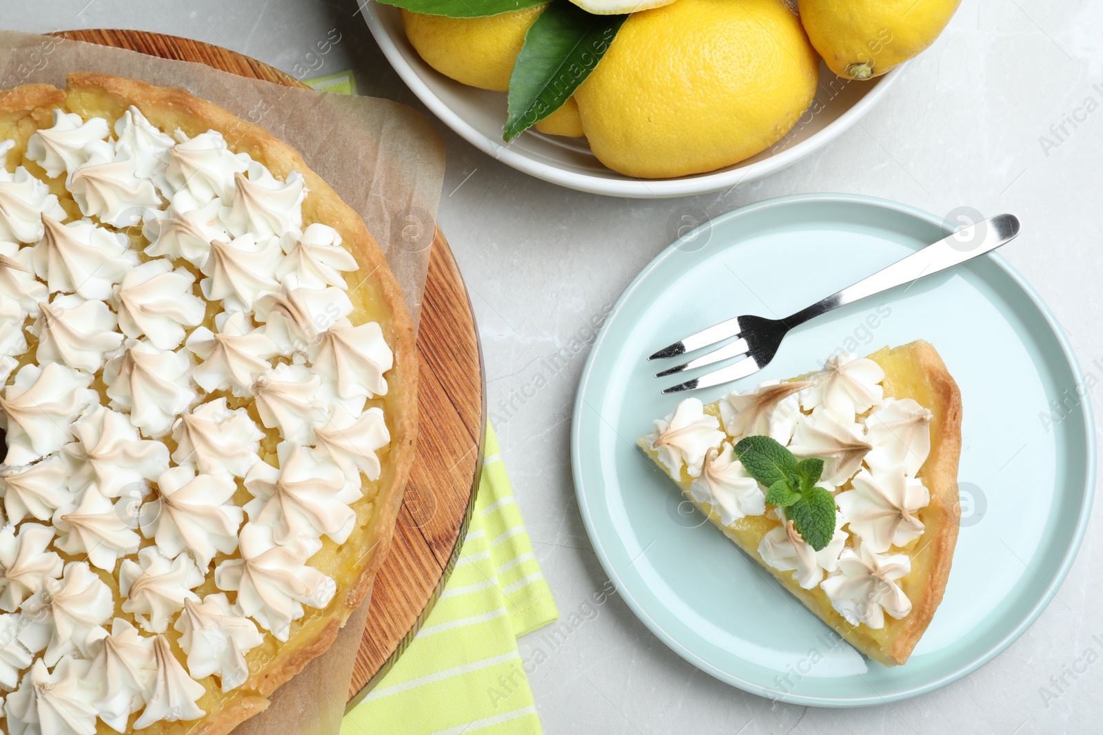 Photo of Cut delicious lemon meringue pie served on light table, flat lay