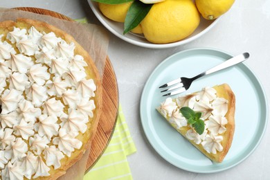 Photo of Cut delicious lemon meringue pie served on light table, flat lay