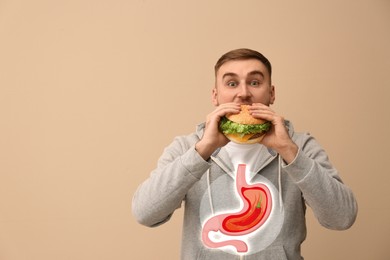 Improper nutrition can lead to heartburn or other gastrointestinal problems. Man eating burger on beige background, space for text. Illustration of stomach with hot chili pepper as acid indigestion