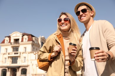 Happy couple with coffee on city street in morning