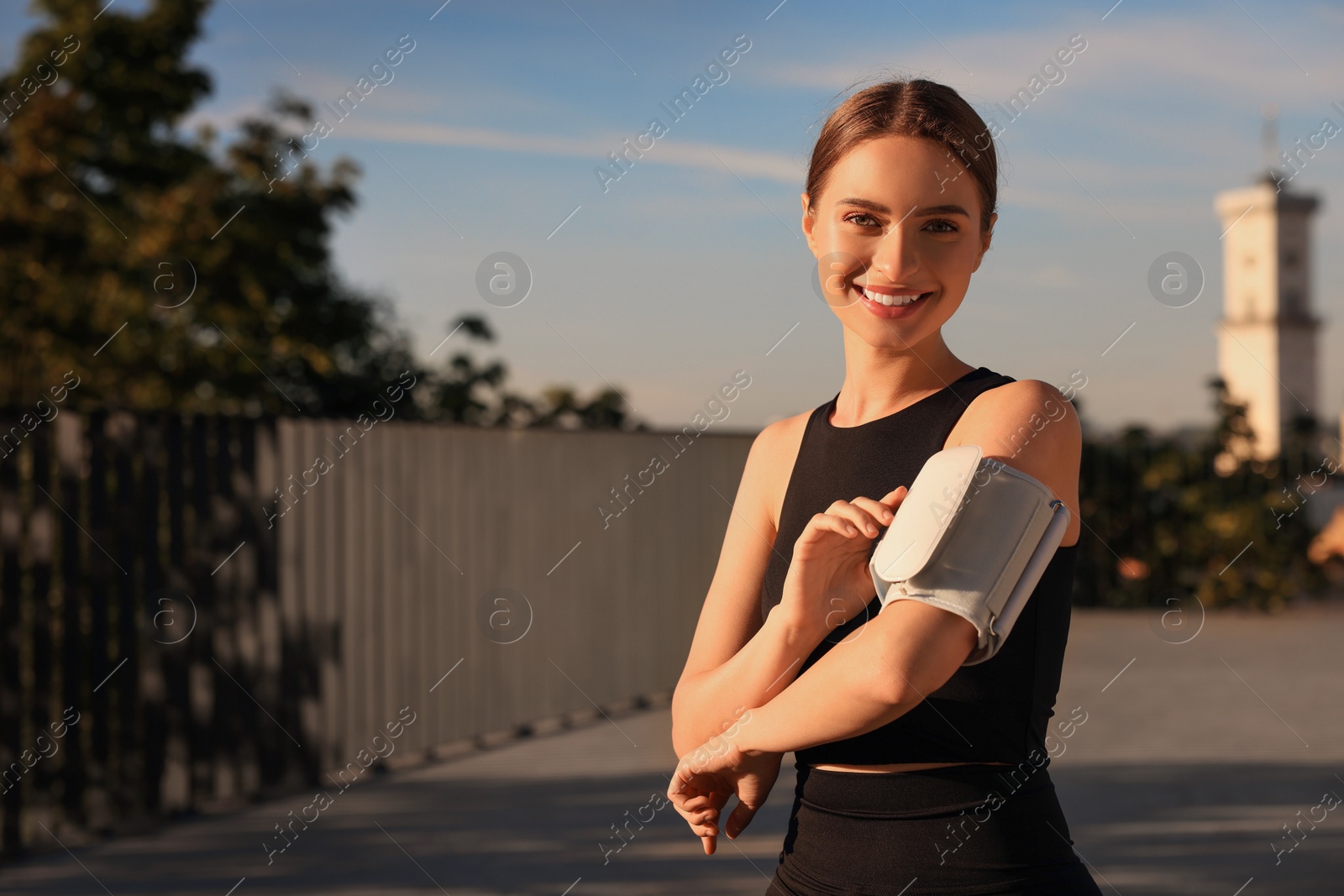 Photo of Attractive happy woman checking blood pressure with modern monitor after training on sunny day. Space for text