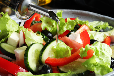 Photo of Adding cooking oil to delicious salad, closeup