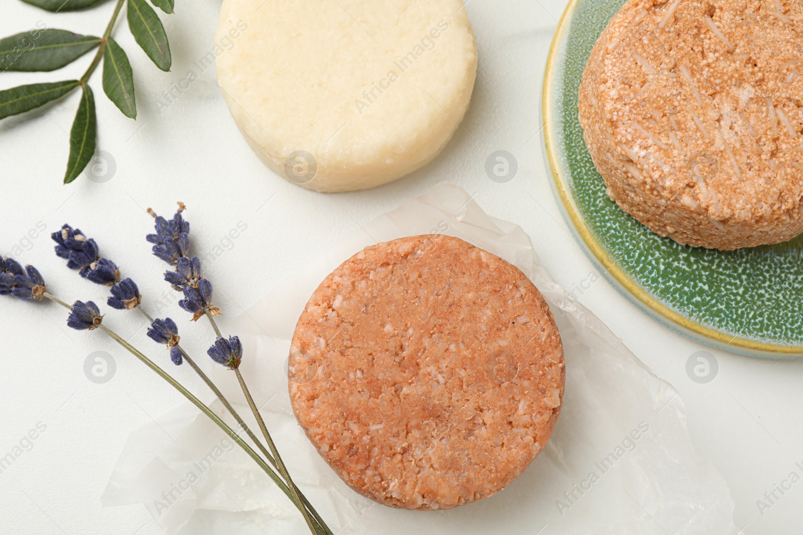 Photo of Solid shampoo bars, green twig and lavender on light table, flat lay