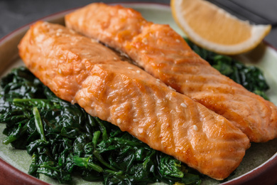 Photo of Tasty salmon with spinach on plate, closeup