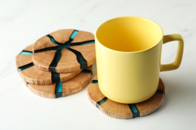 Photo of Mug and stylish wooden coasters on white marble table