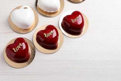 St. Valentine's Day. Delicious heart shaped cakes on white wooden table, flat lay. Space for text