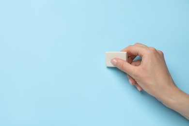 Photo of Woman erasing something on light blue background, closeup. Space for text