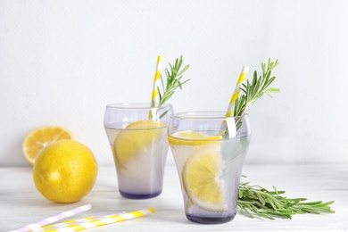 Photo of Tasty refreshing lemon cocktail with rosemary on table