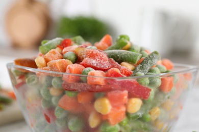 Mix of different frozen vegetables in glass bowl on table, closeup