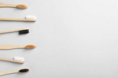 Many different bamboo toothbrushes on white background, flat lay. Space for text