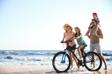 Happy family with bicycle on sandy beach near sea