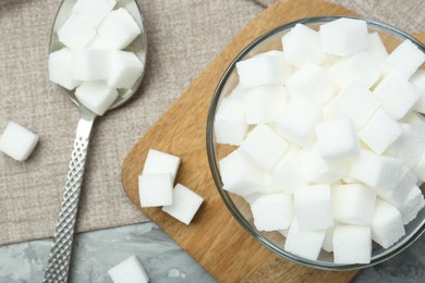 White sugar cubes in glass bowl on grey table, flat lay