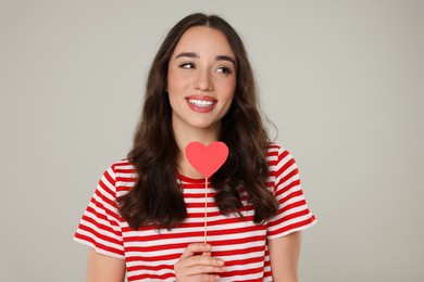 Photo of Beautiful young woman with paper heart on grey background