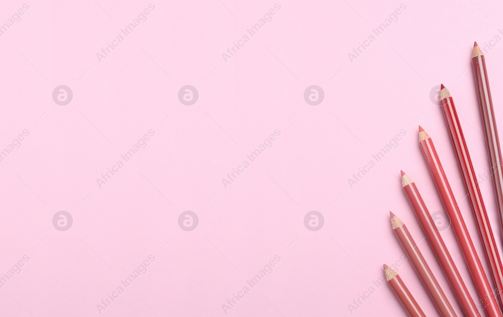 Photo of Lip pencils on pink background, flat lay with space for text. Cosmetic product