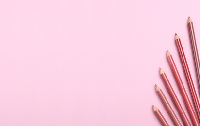 Photo of Lip pencils on pink background, flat lay with space for text. Cosmetic product