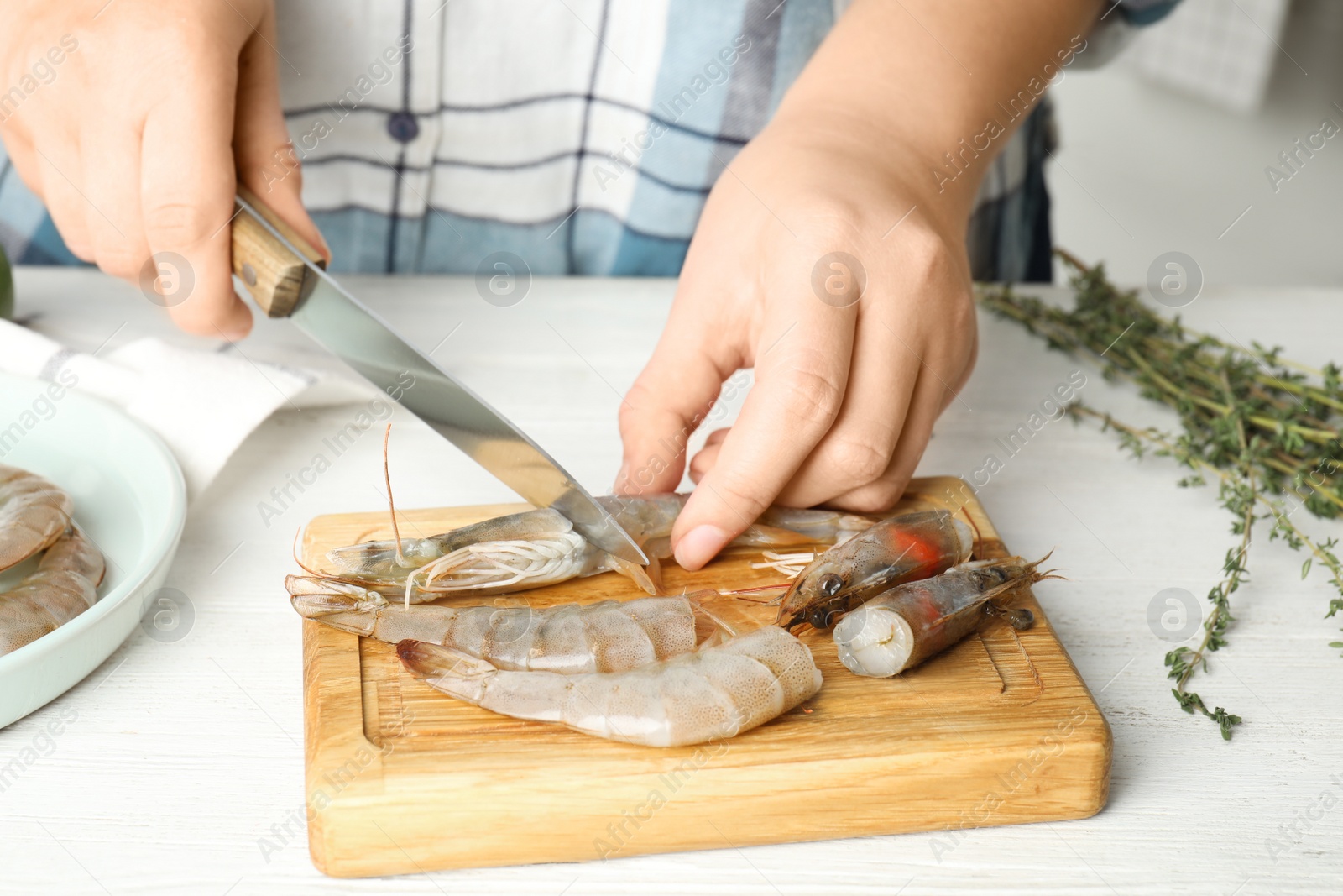 Photo of Woman cutting fresh shrimp at table, closeup