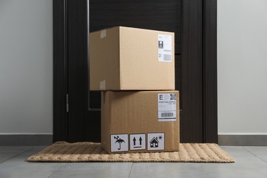 Photo of Cardboard boxes on floor mat near entrance. Parcel delivery service