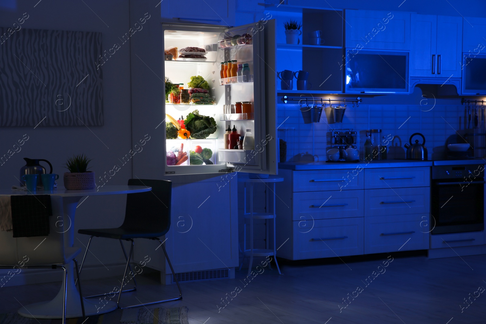 Photo of Stylish kitchen interior with refrigerator full of products at night