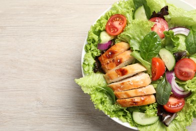 Photo of Delicious salad with chicken and vegetables on wooden table, top view. Space for text