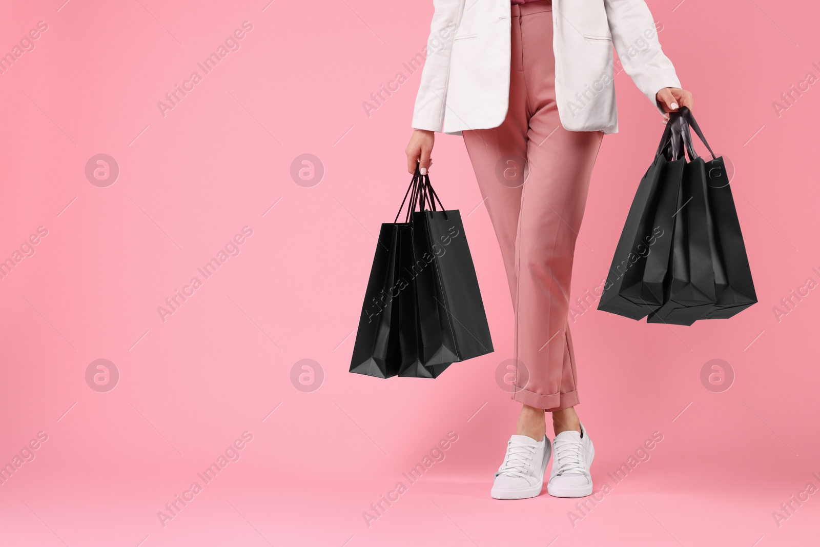 Photo of Woman with shopping bags on pink background, closeup. Space for text