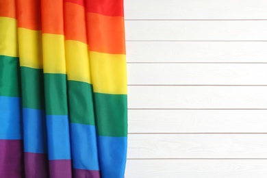 Bright rainbow gay flag on wooden background, top view with space for text. LGBT community