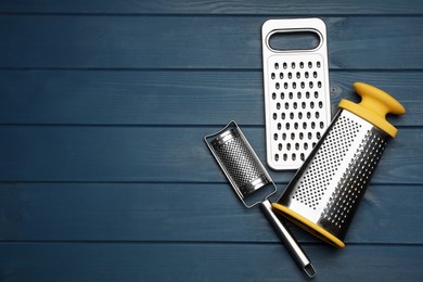 Different modern graters on blue wooden table, flat lay. Space for text