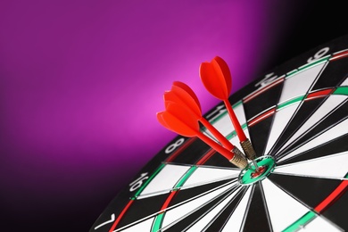 Red arrows hitting target on dart board against purple background. Space for text