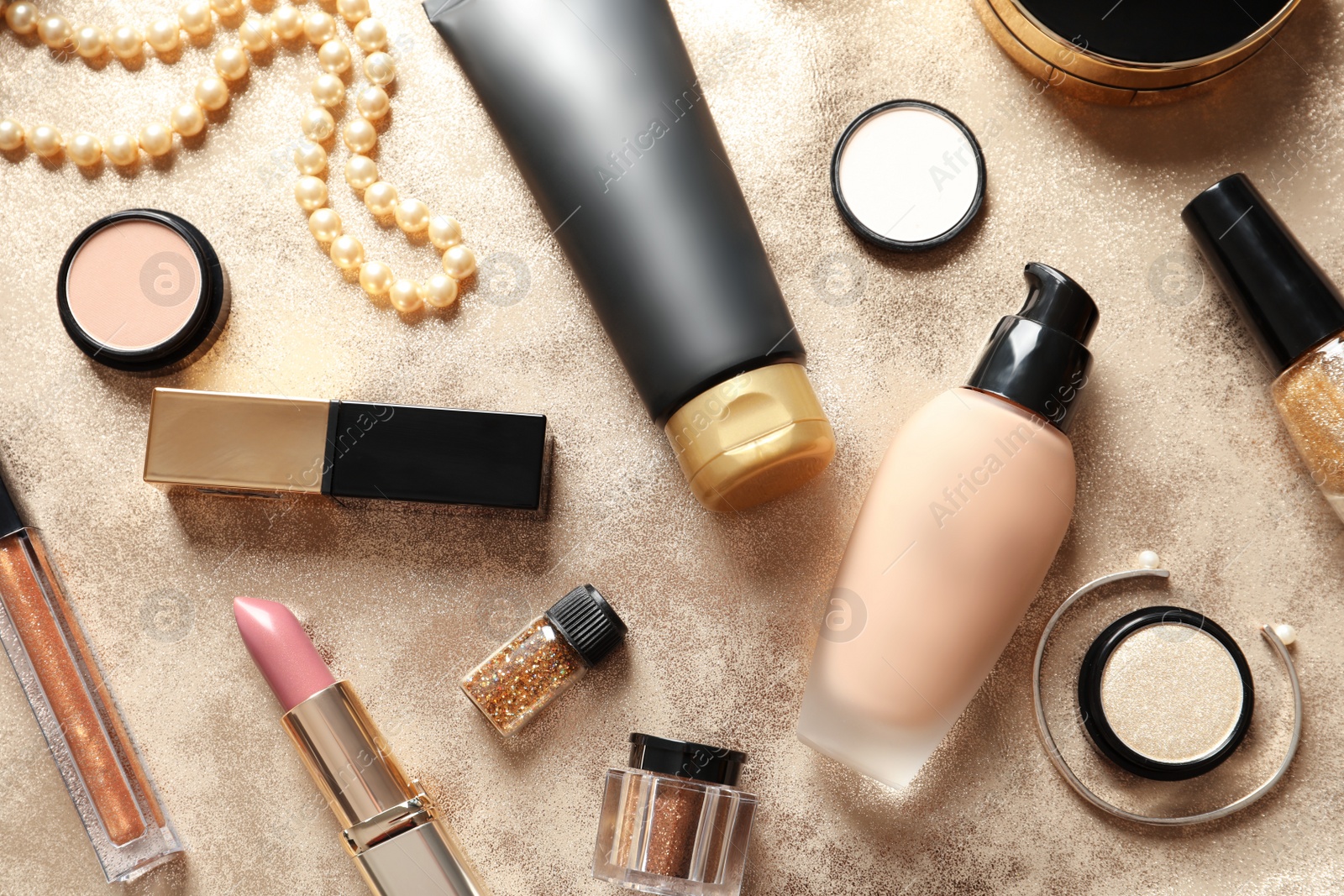 Photo of Different luxury makeup products on gold background, flat lay