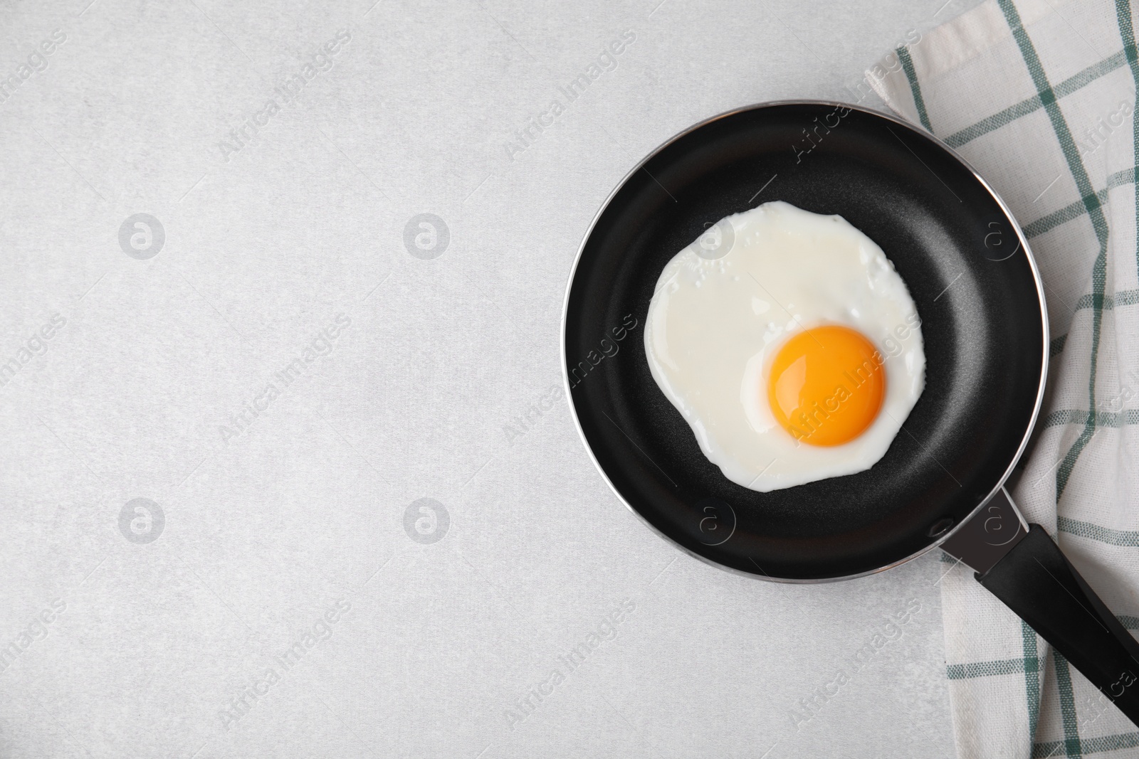 Photo of Tasty fried egg in pan on light grey table, flat lay. Space for text