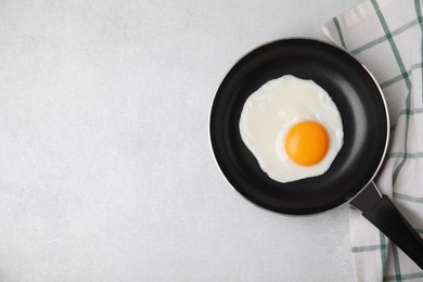 Tasty fried egg in pan on light grey table, flat lay. Space for text