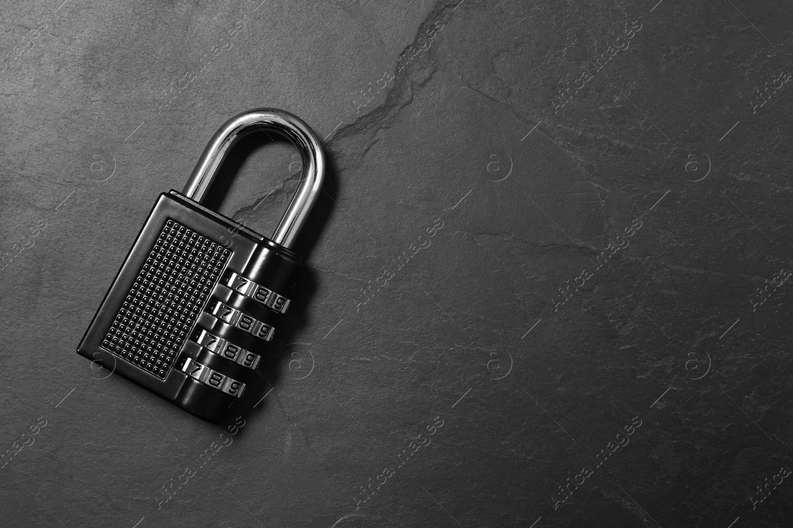 Photo of One steel combination padlock on black table, top view. Space for text