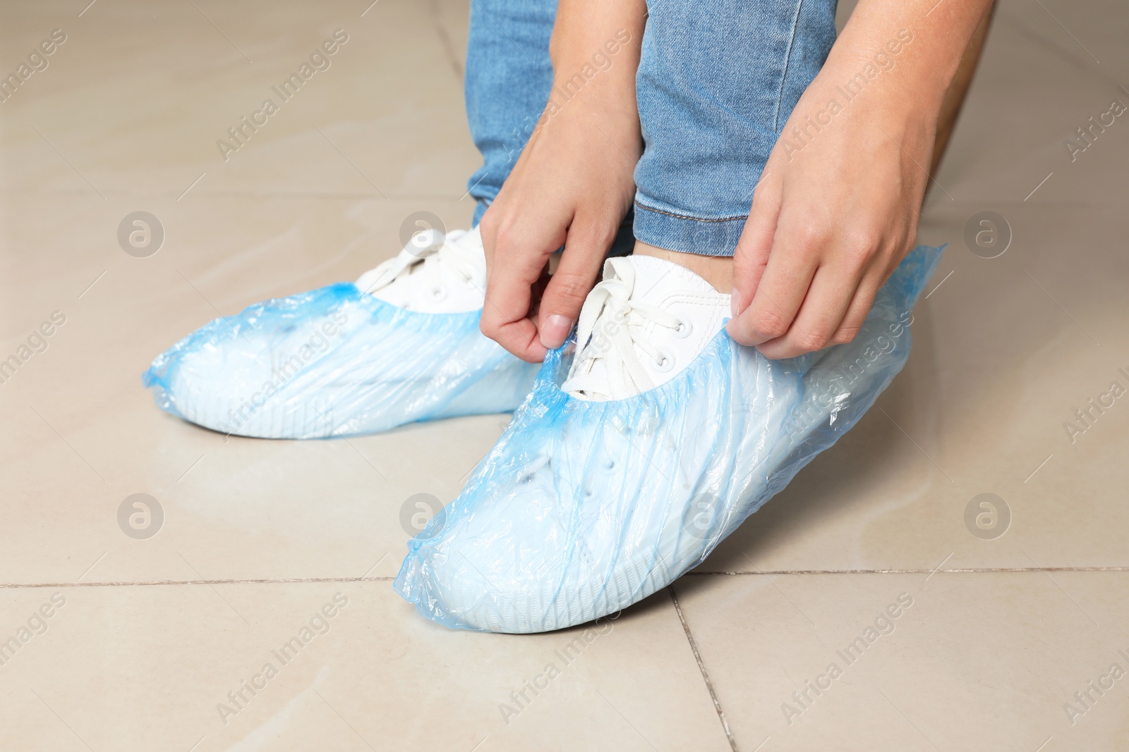 Photo of Woman putting on blue shoe covers, closeup