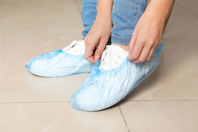 Photo of Woman putting on blue shoe covers, closeup