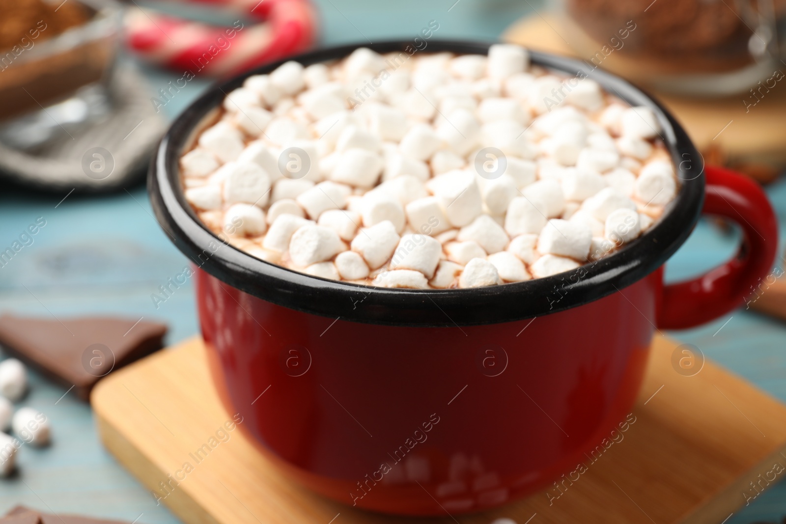 Photo of Tasty hot chocolate with marshmallows on light blue wooden table, closeup