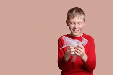 Photo of Happy boy popping bubble wrap on beige background, space for text. Stress relief