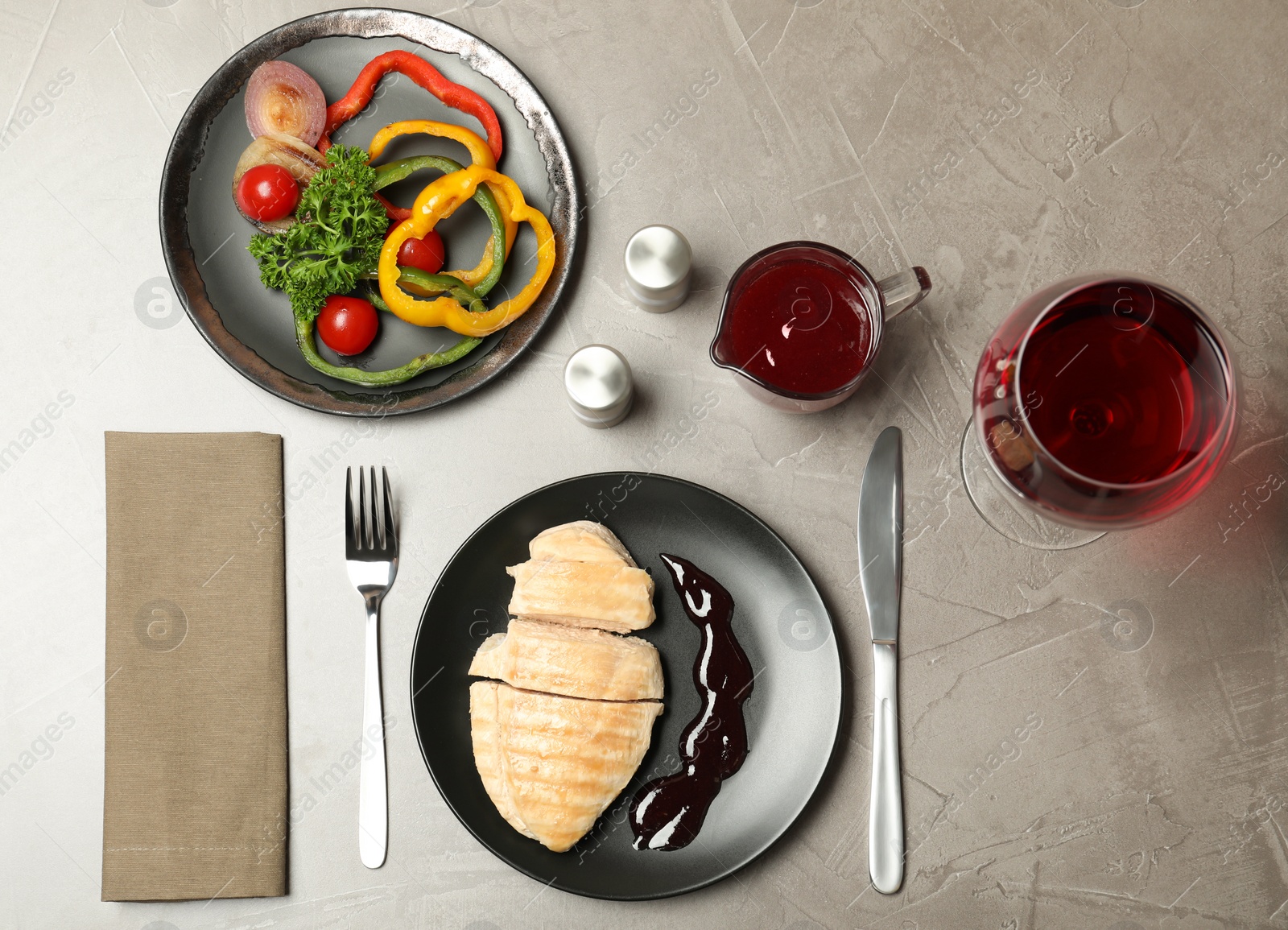 Photo of Chicken meat served with garnish, sauce and wine on grey background, flat lay