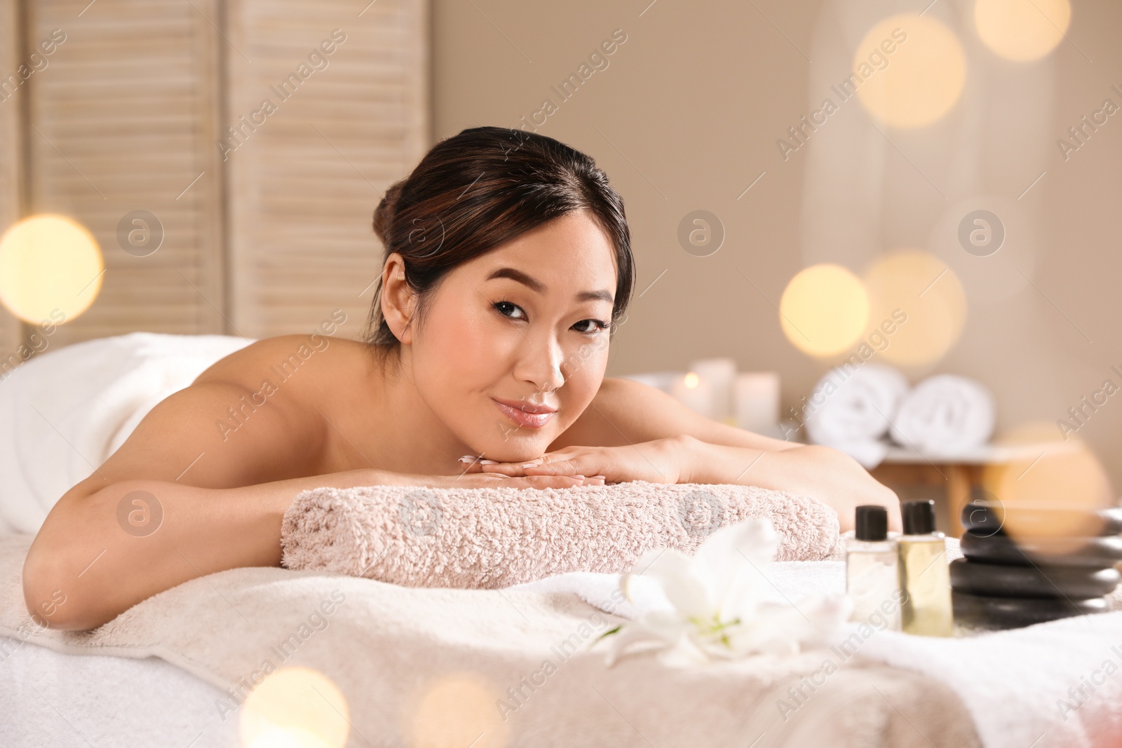 Photo of Beautiful Asian woman lying on massage table in spa salon. Space for text