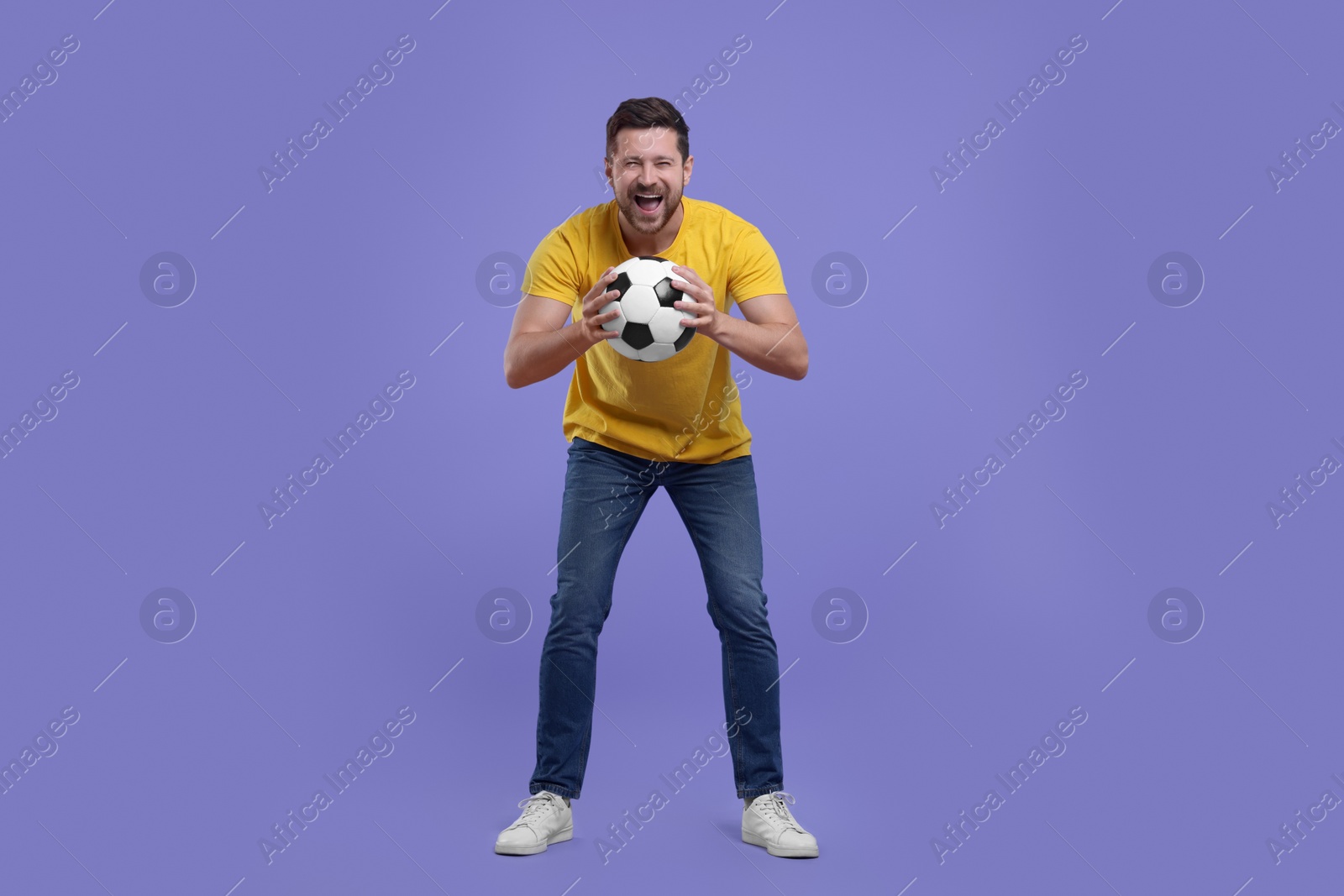 Photo of Emotional sports fan with ball on purple background
