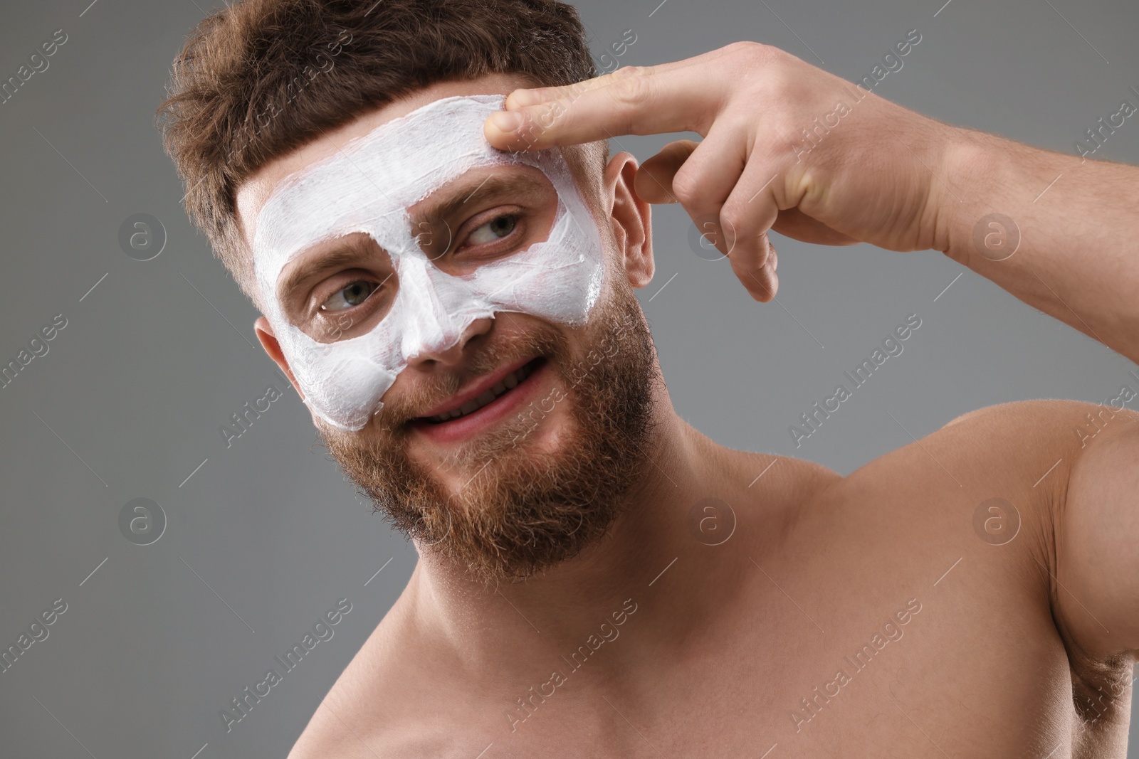 Photo of Handsome man with facial mask on his face against grey background