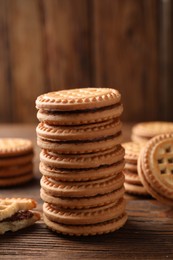 Photo of Tasty sandwich cookies with cream on wooden table, closeup