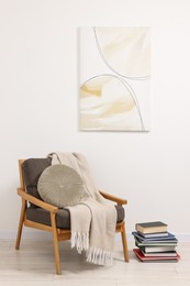 Photo of Stylish living room interior with comfortable armchair, blanket and stack of books