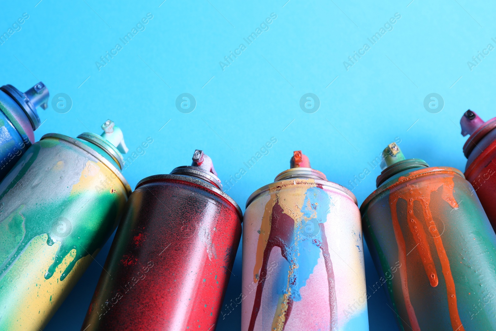 Photo of Many spray paint cans on light blue background