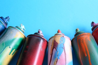 Photo of Many spray paint cans on light blue background